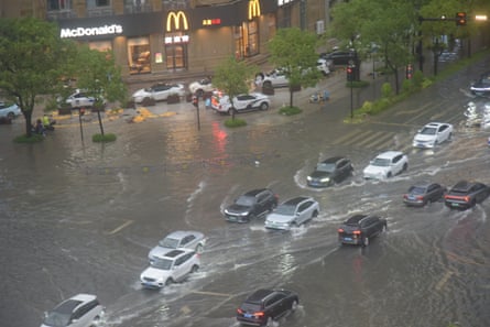 Cars drive on a flooded street in Zhejiang province