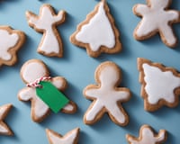 Adriann Ramirez' black pepper soft gingerbread cookies in several familiar shapes with icing on top, such as the 'gingerbread man' motif, a traditional angel, a Christmas tree, and a five-pointed star. Two green gift tags have been added to the human-shaped biscuits.