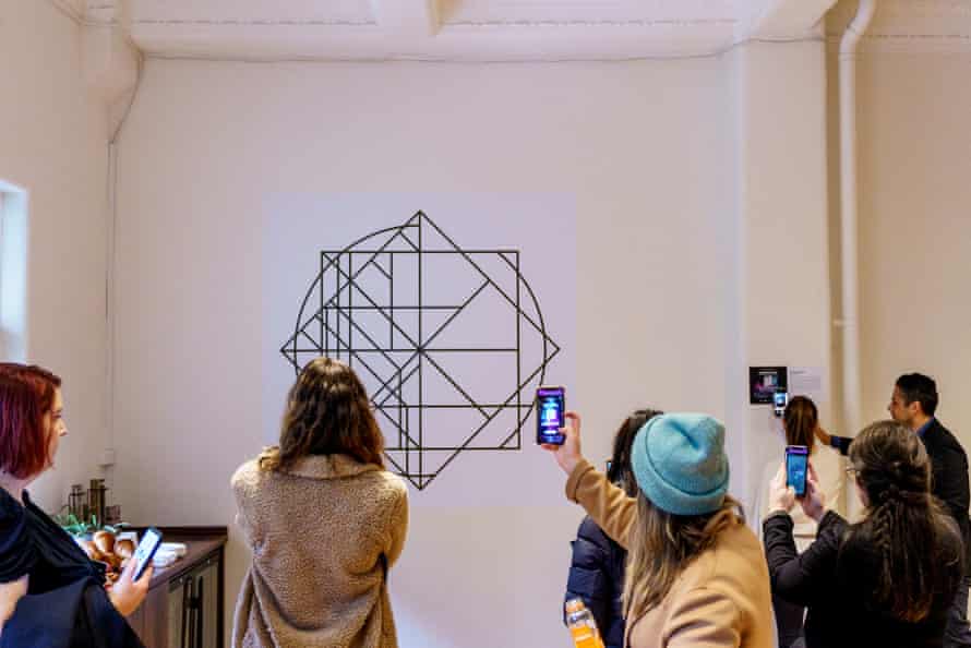 Audience members hold up their smartphones to access the augmented reality elements of Portal Glitch by Sue Beyer