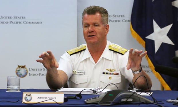man gestures while seated at table