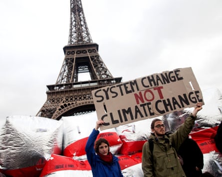 Climate demonstrators hold up a sign near the Eiffel Tower during demonstrations during the last day of Cop21.