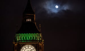 Big Ben and the houses of parliament at night-time, with a bright moon shining above