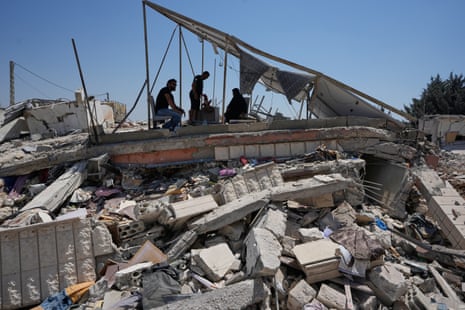 Three people sat atop the rubble of their home.