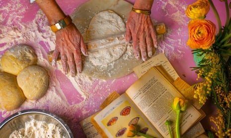 Hands rolling out dough with a recipe book open nearby