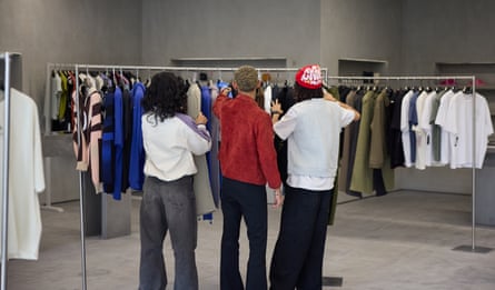 A group of young people in front of a clothing rack.