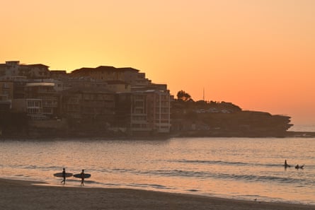 Sunrise at Bondi Beach, with two surfers entering the water