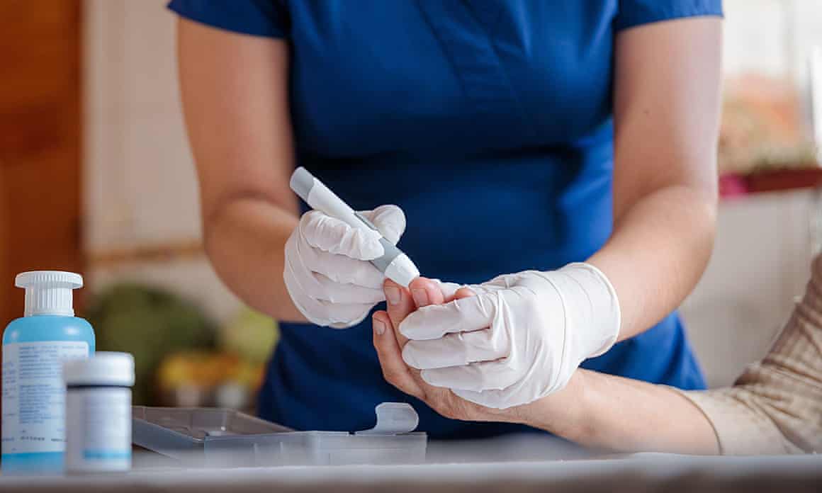 A nurse administers a finger prick test to measure a patient's blood glucose level