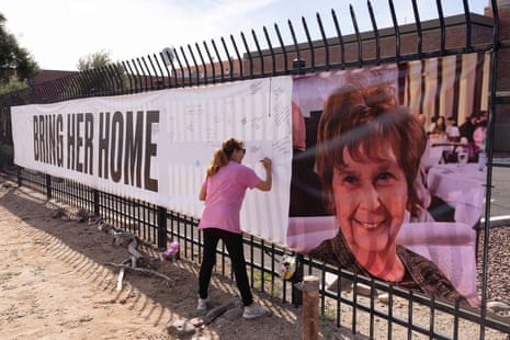 a person writes a message of support on a large banner titled 'bring her home' with a photo of a woman