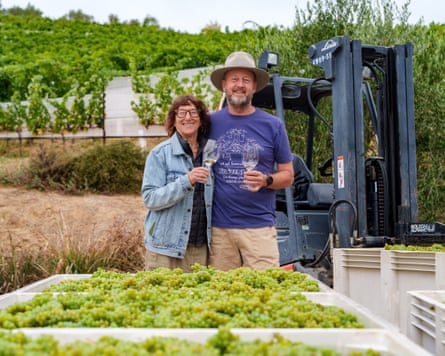 A woman and man pose in front of their winery field