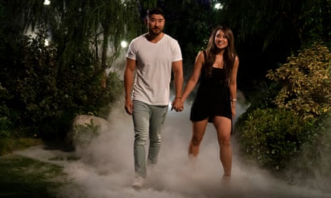 A couple stride out of a fake forest, hand in hand, with dry-ice smoke billowing around their ankles