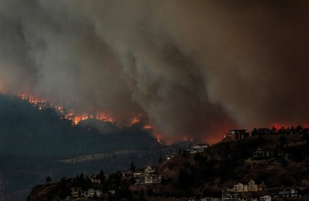 Smoke and flames from wildfires threaten homes across Okanagan Lake in West Kelowna, British Columbia.