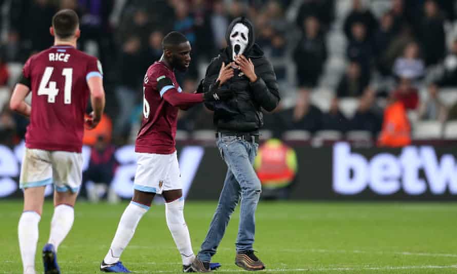 One of the West Ham pitch invaders was wearing a Scream mask and is ushered away by Arthur Masuaku.