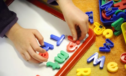 Close up of a child playing with a multi-coloured letter set on a table