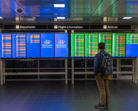 man with backpack stands by signs with flight information