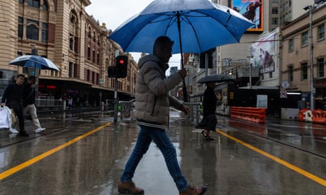 People hold umbrellas as they walk in Melbourne CBD