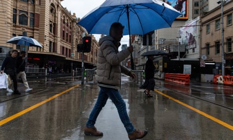 A man walks with an umbrella through a wet street