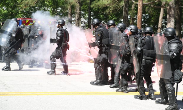 Officers in riot gear dodge an exploding firework at Stone Mountain Park.
