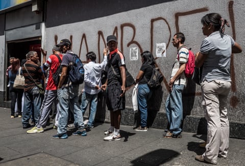 People queue to withdraw money from a cash machine in Venezuela