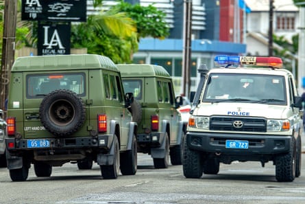 A patrolling police vehicle passes military vehicles on the streets of Suva on December 23, 2022, a day after the government announced a post-election deployment to maintain “law and order”.