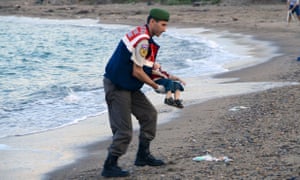 A Turkish police officer carries Alan’s body.