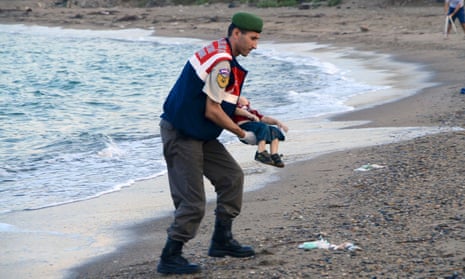 A Turkish police officer carries a young drowned boy