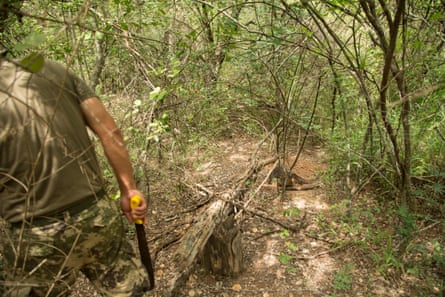 A soldier uses a machete to cut his way through scrub forest