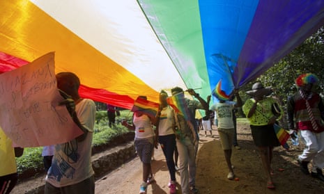 The 2015 Pride Uganda parade, under a giant raiblow flag, in Entebbe