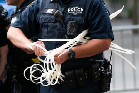 An NYPD officer gets zip ties ready handcuff protesters during a “Defund the Police” protest.