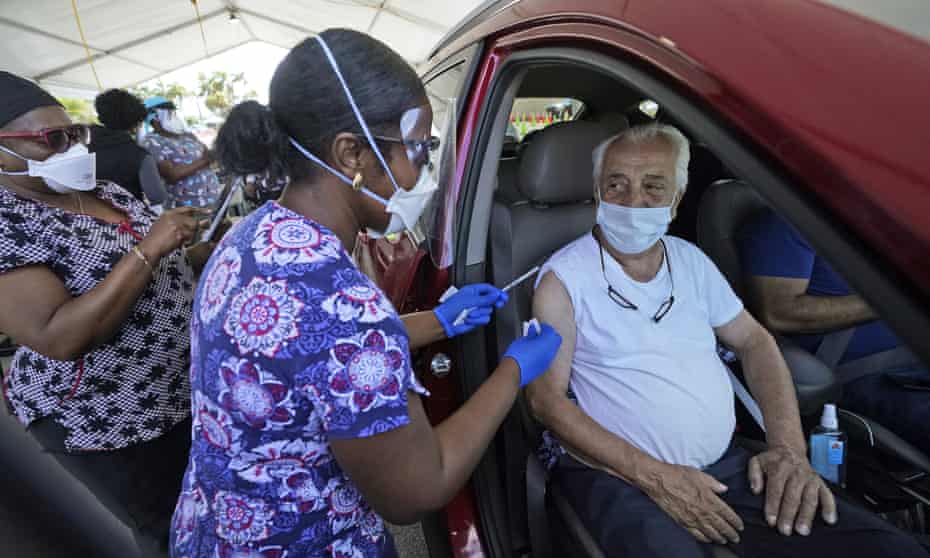 Miguel Garcia, 78, right, prepares to receive a dose of the Pfizer’s Covid-19 vaccine, at the Miami-Dade County Tropical Park vaccination. Some are calling for age limits on vaccine eligibility to be lifted as younger people are more likely to spread the virus.