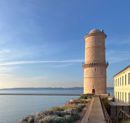 A picture of the sea and a lighthouse on the shoreline on a sunny day with an almost clear blue sky.