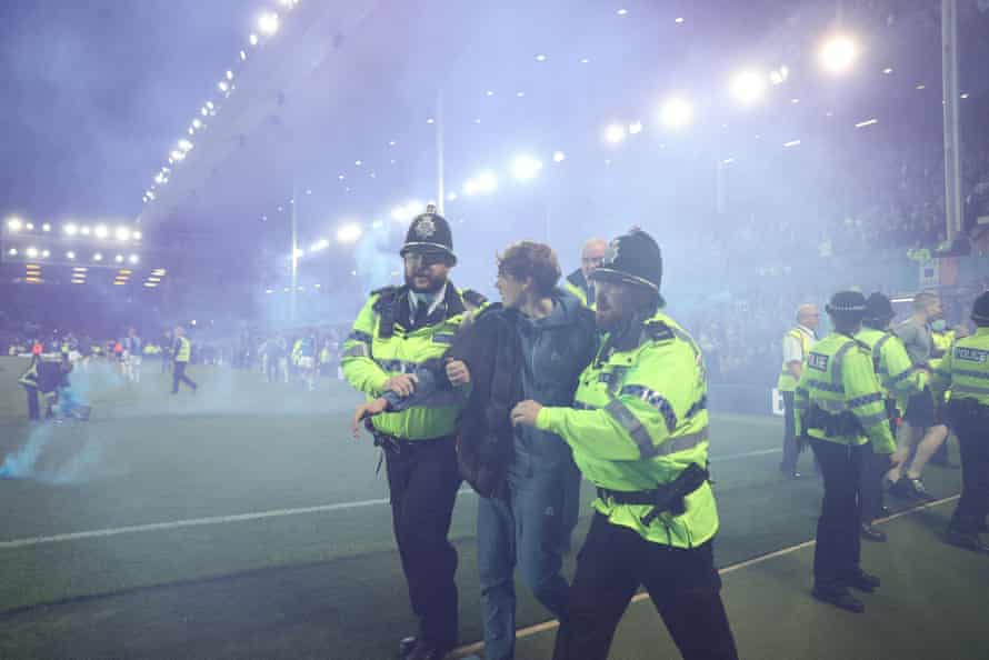 Police officers and stewards try to clear away fans after a pitch invasion at Goodison Park