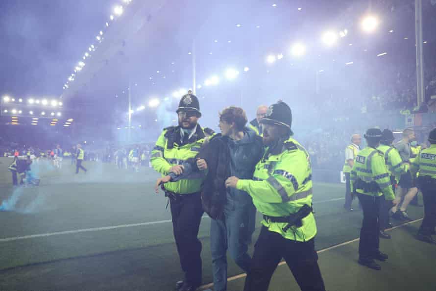 Police officers and stewards attempt to clear away fans after a pitch invasion at Goodison Park