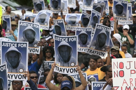 A large group of people hold posters bearing a picture of a Black teen and ‘Justice for Trayvon’.