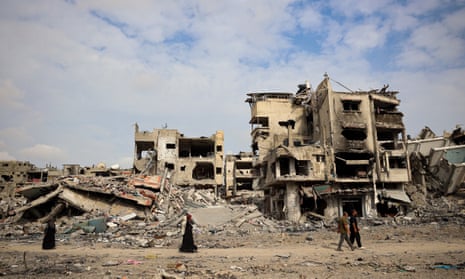 People walk past damaged buildings in Khan Younis on 8 April after Israeli forces withdrew.