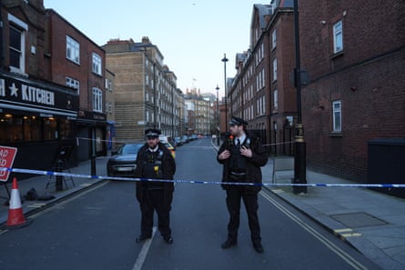 Two police officers stand by a road closure at dusk