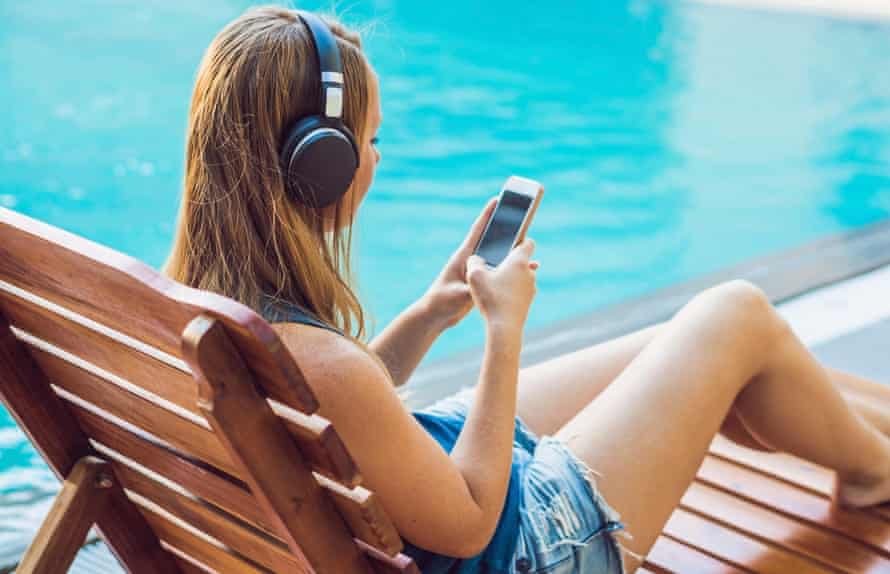 Someone uses their mobile phone to play songs while relaxing with headphones on during a summer vacation