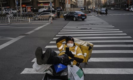 A courier waits for business at a normally busy intersection in Beijing on Friday.