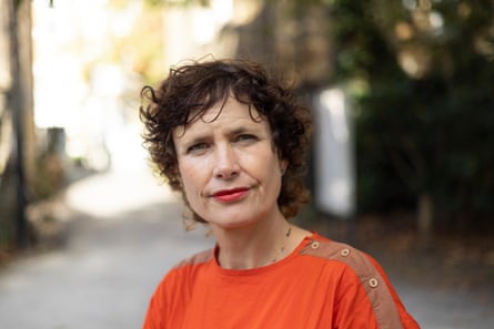 A woman wearing an orange top sits for the camera.