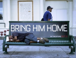 A homeless man sleeps on a bench in Los Angeles, California.