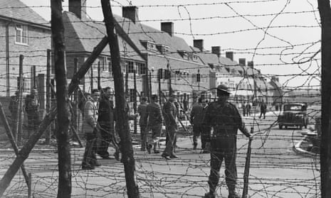 Barbed wire and an armed guard outside a housing estate used as an internment camp