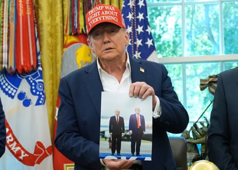President Donald Trump holds a photo of himself with Russian President Vladimir Putin during an announcement in the Oval Office of the White House