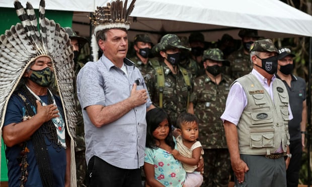 President Jair Bolsonaro listens to national anthem next to an indigenous person at the Yanomami tribe reservation bordering Venezuela in São Gabriel da Cachoeira, Amazonas state, Brazil, on Thursday.