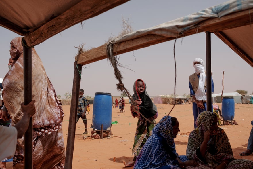 Malian refugees wait by a food distribution point in M’bera camp