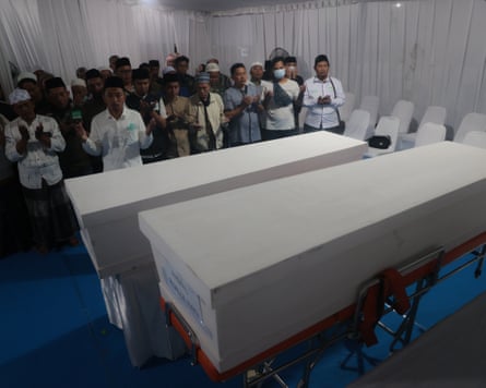 Men pray near the coffins containing the bodies of two of the building collapse victims at the police hospital in Surabaya, East Java, on Sunday.