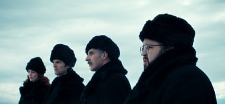 A white woman and three white men wearing winter hats and coats look ahead