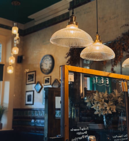 A pub room with a dark green ceiling, woodwork and ribbed glass pendant light shades
