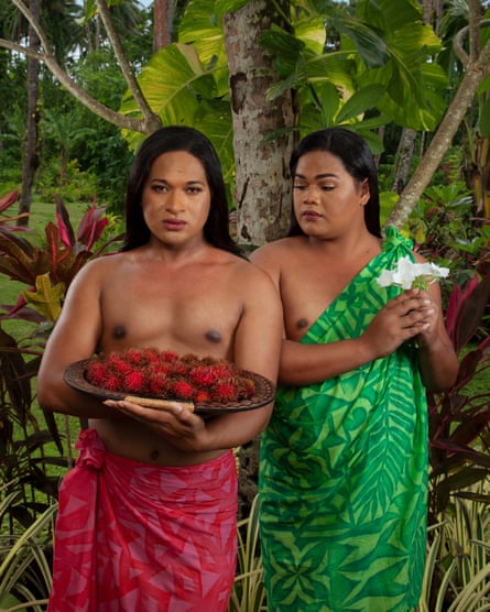 Two feminine-looking men pose in bright traditional wraparound clothes in a jungle setting, mimicking the South Pacific paintings of Gauguin