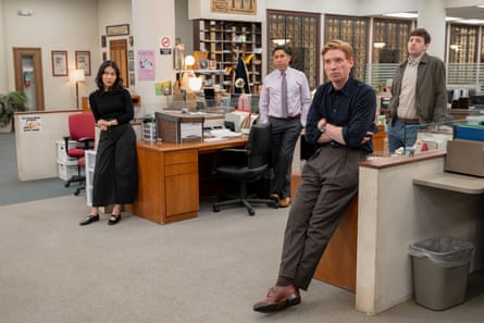 One woman and three men standing in an office