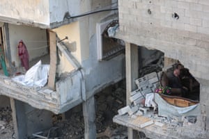 A woman clears debris from her destroyed home