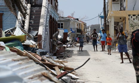 Residents wait in front of the houses destroyed by Irma during Emmanuel Macron’s visit to St Martin on Tuesday, 12 September.